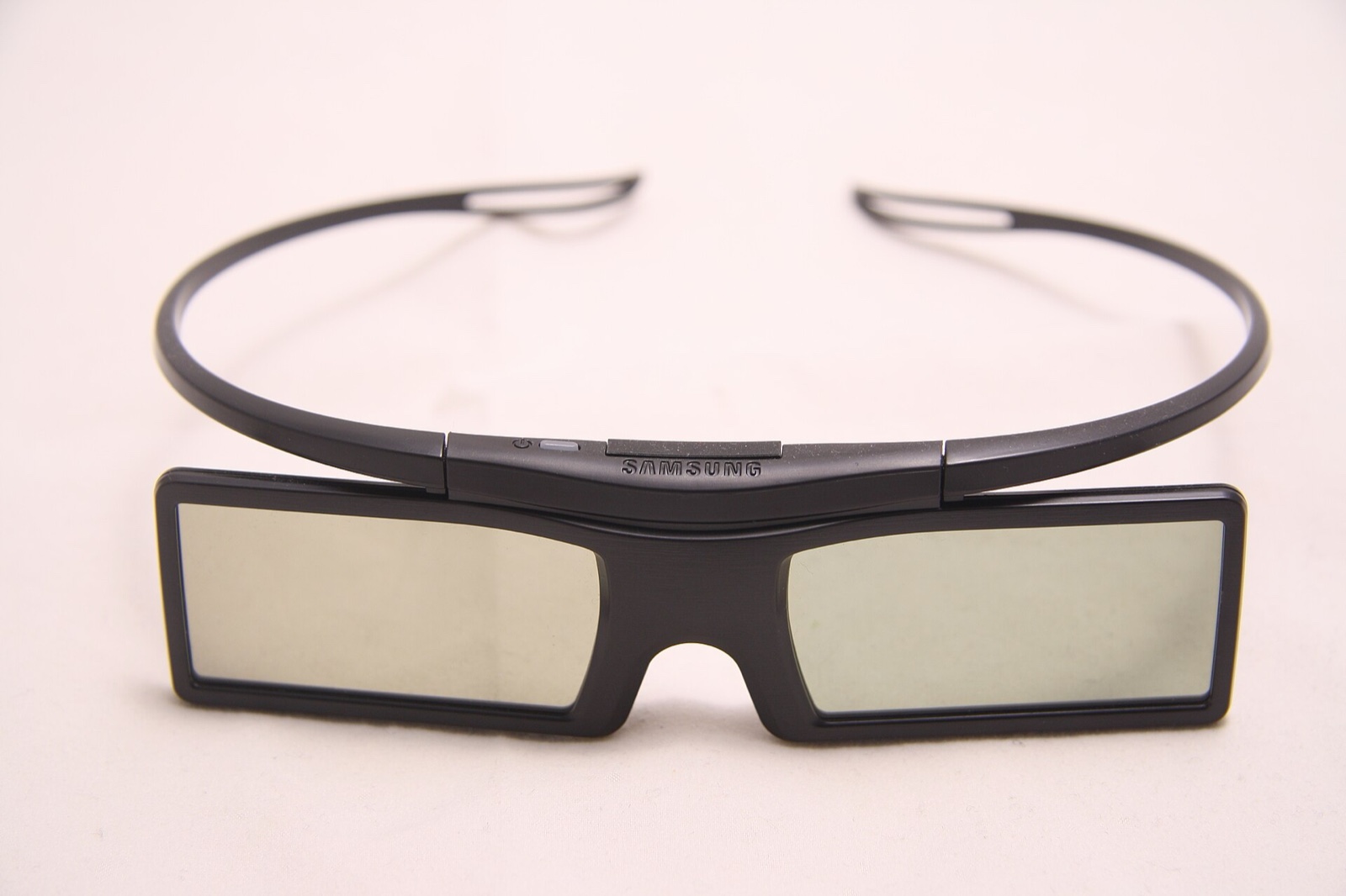A pair of black Samsung active 3D glasses seen from the front, with a power button above the bridge and thin wraparound temples.