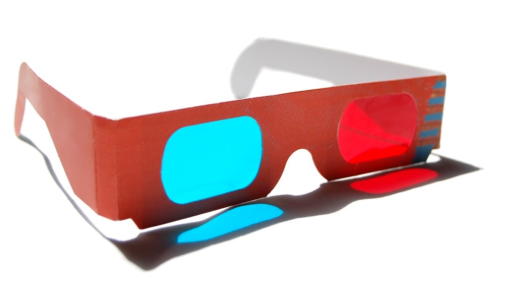 A pair of paper anaglyph glasses with one red lens and one cyan lens.