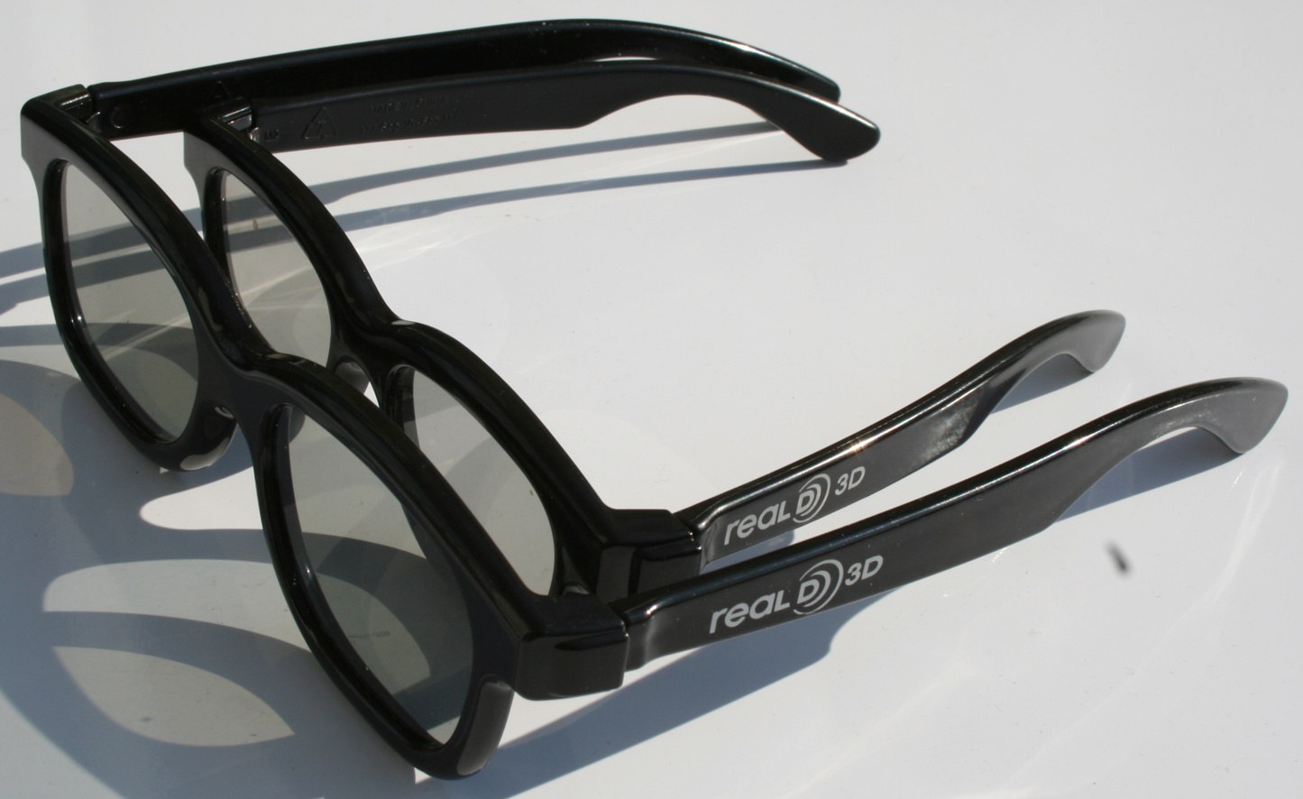 Two pairs of black plastic RealD 3D cinema glasses, an adult pair and a smaller child's pair, with the RealD 3D logo on the temples.