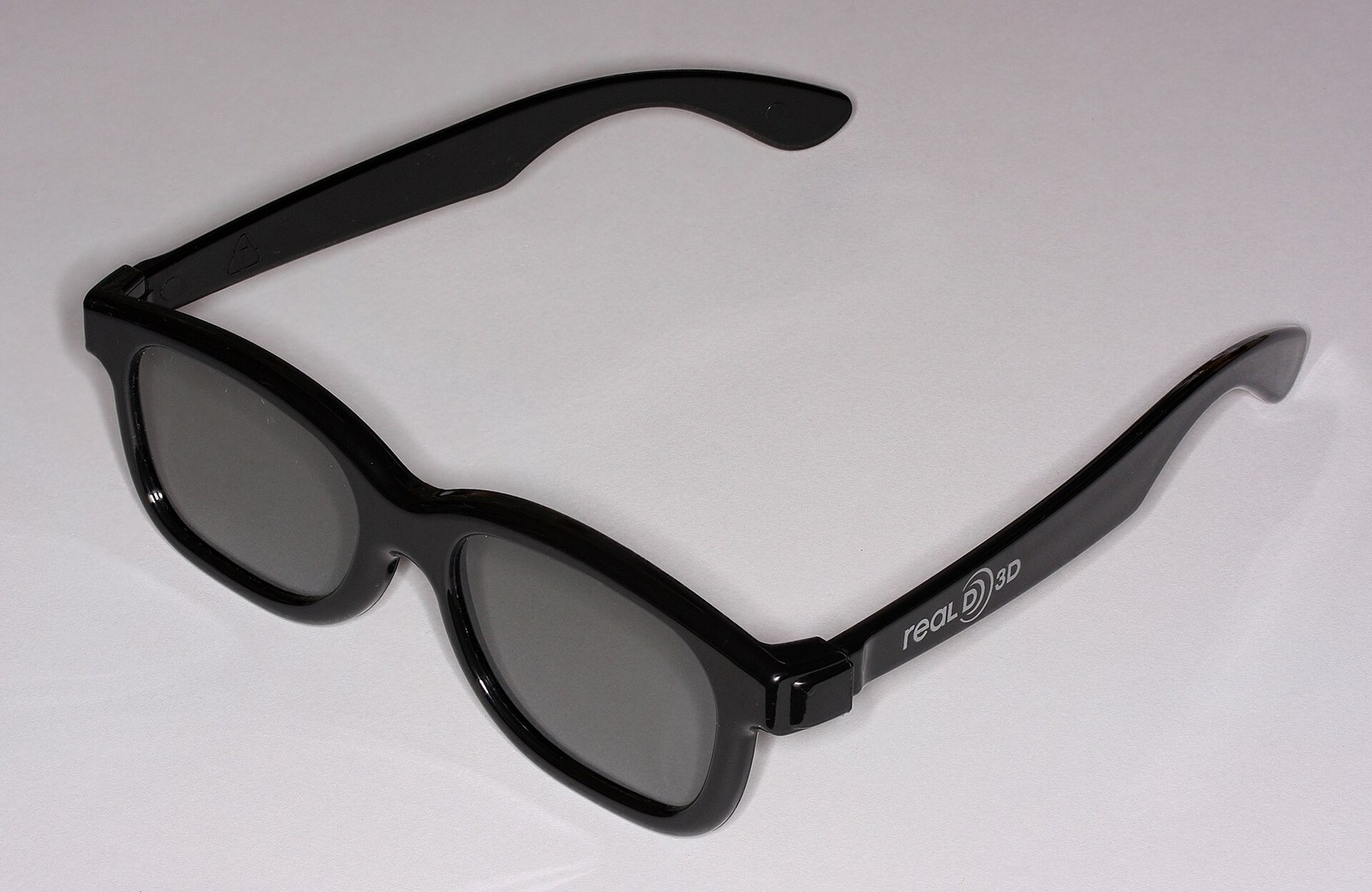 A pair of black plastic RealD 3D glasses with grey lenses.