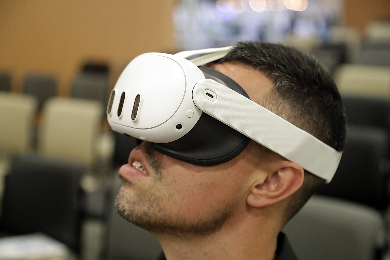 Mann mit einer weißen VR-Brille vom Typ Meta Quest 3, der den Kopf nach oben dreht.