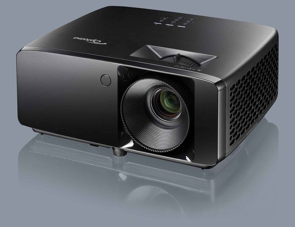 Un vidéoprojecteur noir vu de trois quarts, objectif au premier plan, posé sur une surface grise.